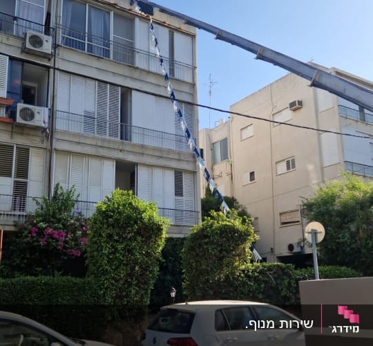מנוף הרמה מתוח לכיוון הקומה העליונה של בניין מגורים